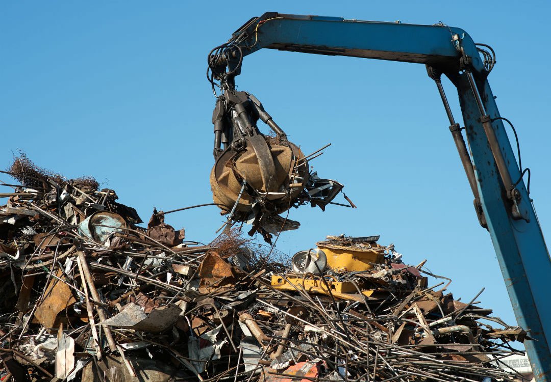 Crane grabber lifting industrial scrap at a factory yard